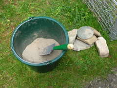 Bucket with sand, hand shovel and stones